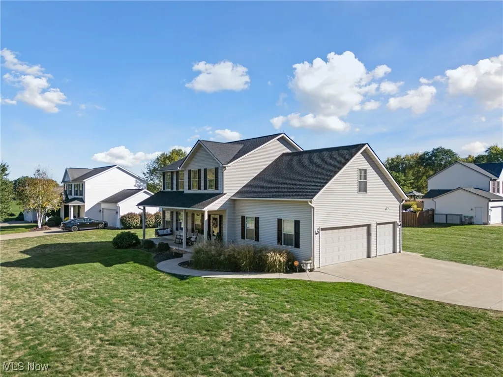 Traditional-style home with a front yard, a porch, driveway, a 3 car garage, and a shingled roof
