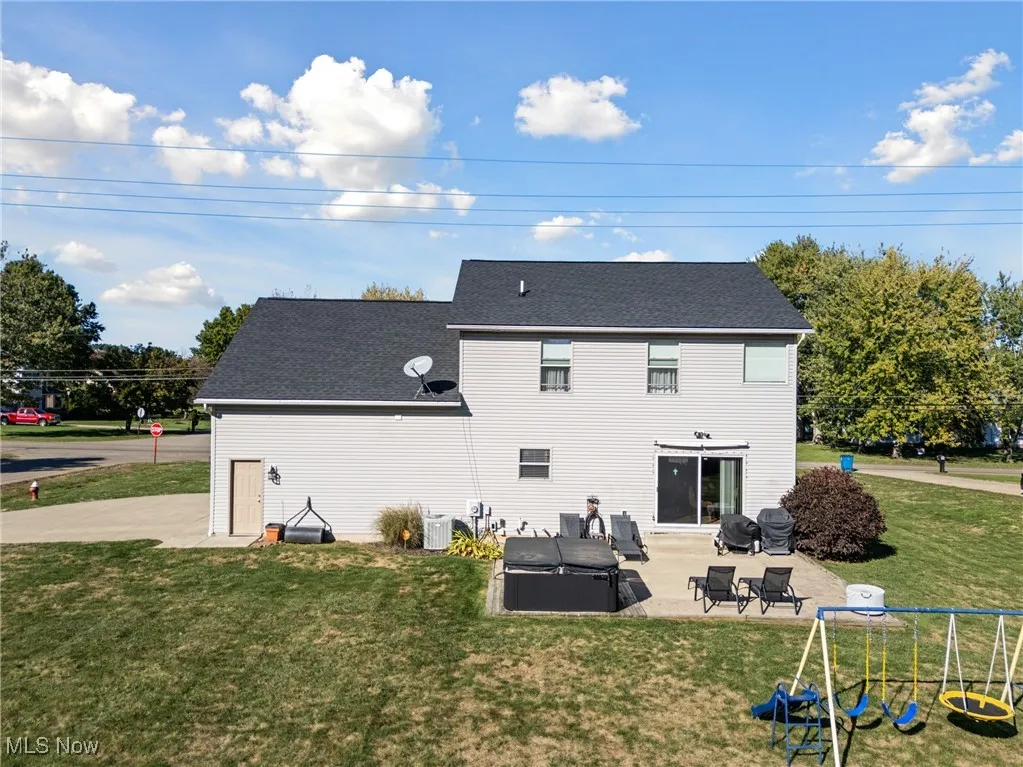 Rear view of property with a lawn, a shingled roof, and a patio