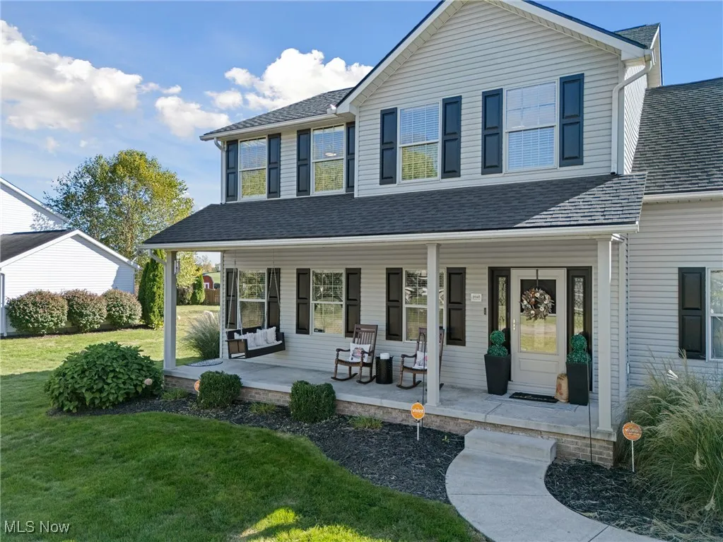 View of front of house with a porch, a front lawn, and roof with shingles
