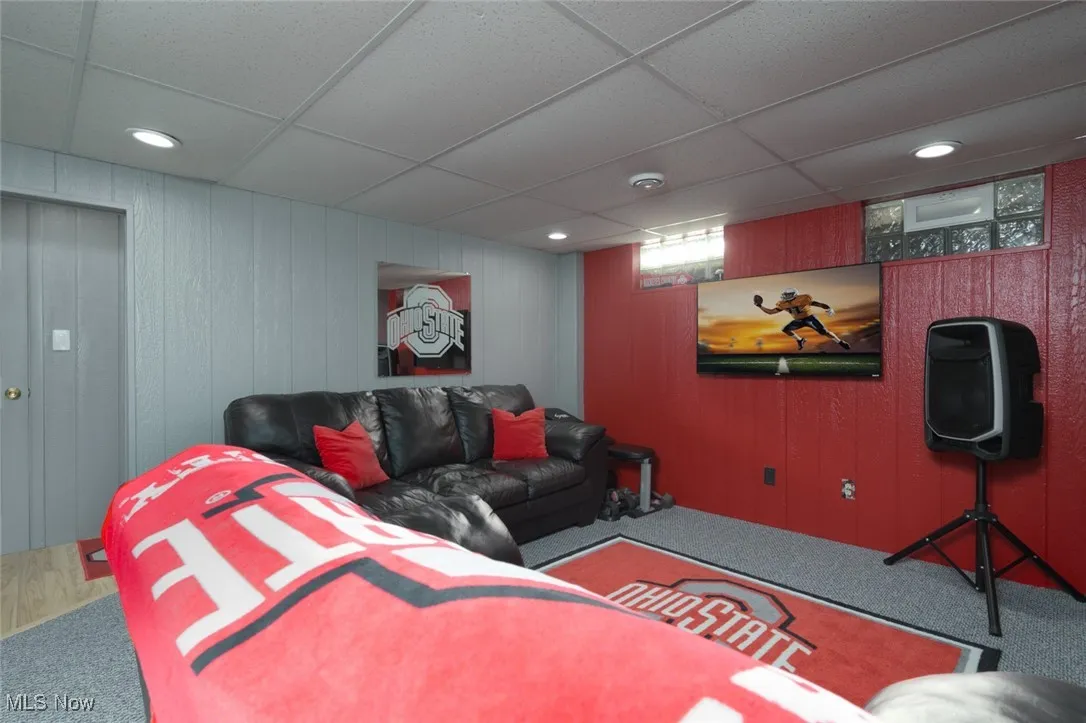 Carpeted living room with a paneled ceiling, recessed lighting, and wooden walls