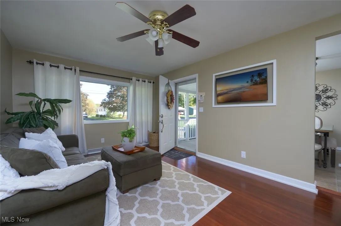 Living area with dark wood finished floors, plenty of natural light, and a ceiling fan