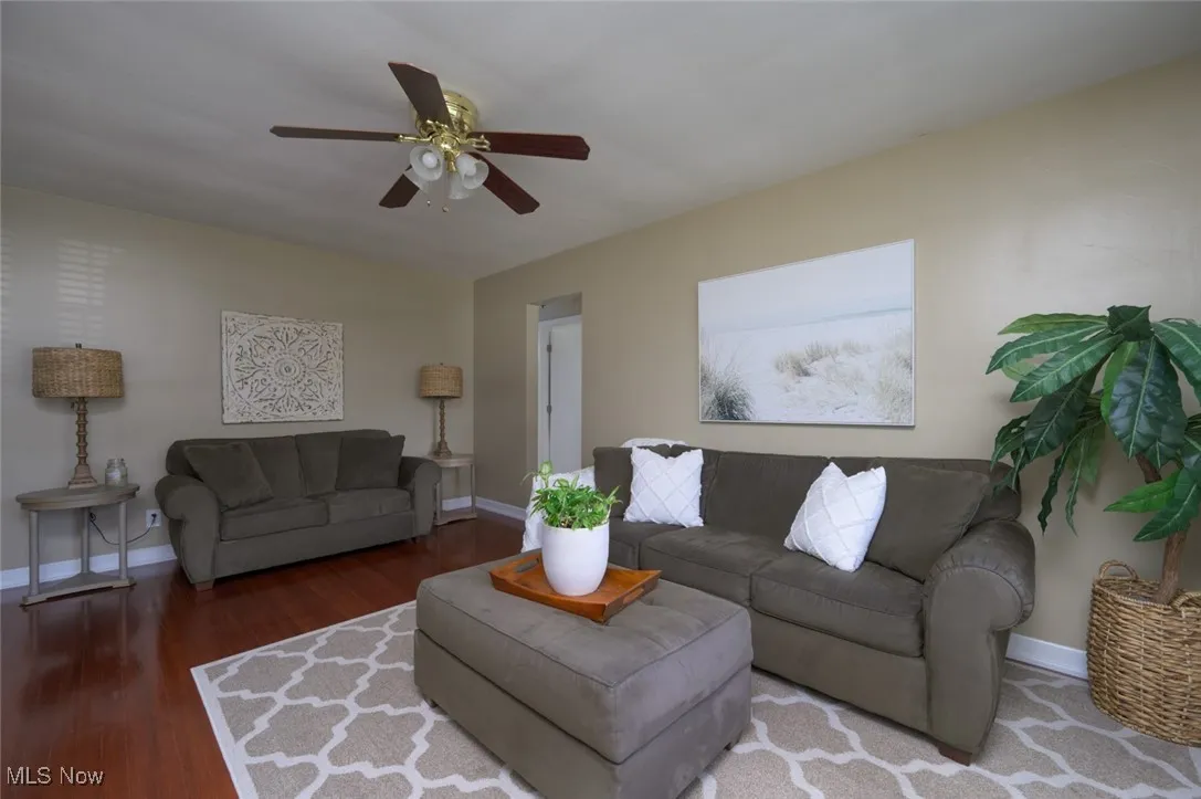 Living room featuring dark wood-type flooring and ceiling fan