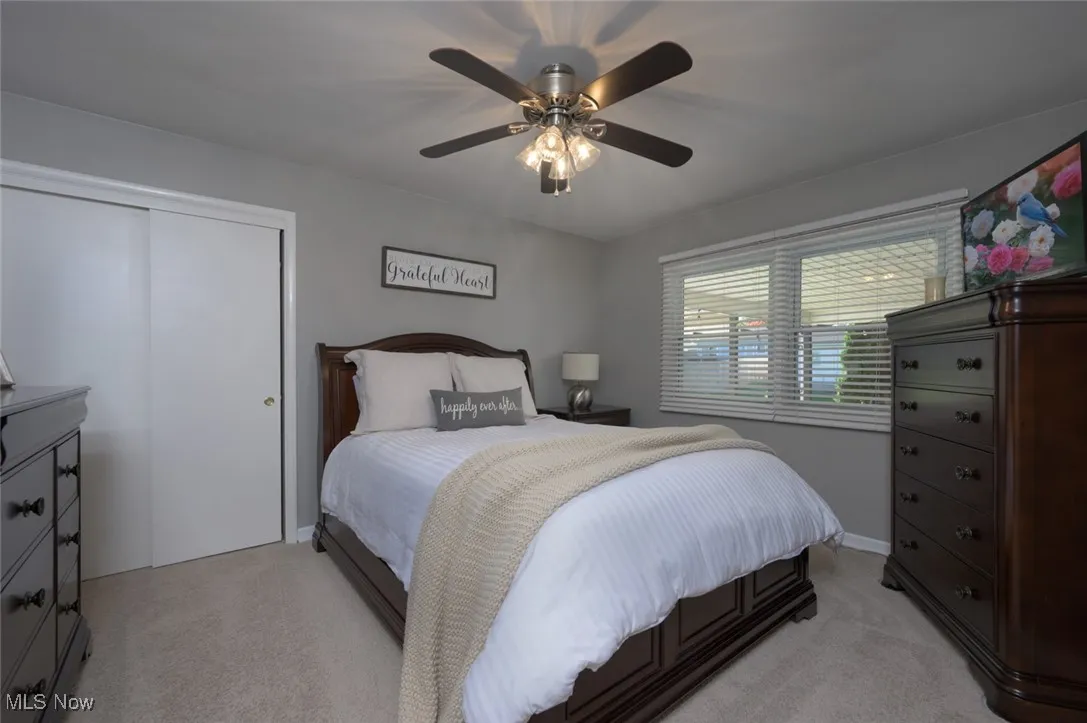 Bedroom featuring light carpet, ceiling fan, and a closet