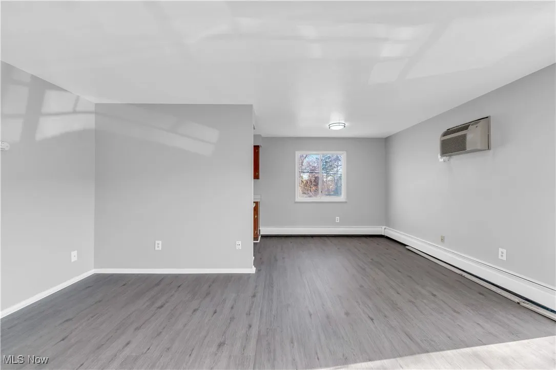 Spare room featuring light wood-style flooring, a baseboard heating unit, and a wall mounted AC
