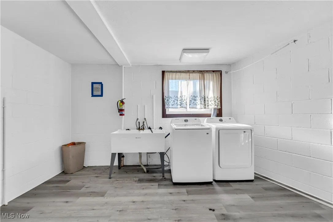 Laundry room featuring concrete block wall, light wood-style floors, and washer and dryer
