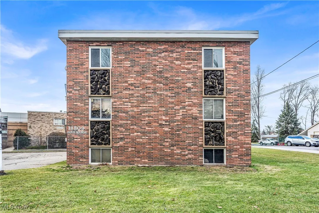 View of property exterior featuring brick siding and a lawn