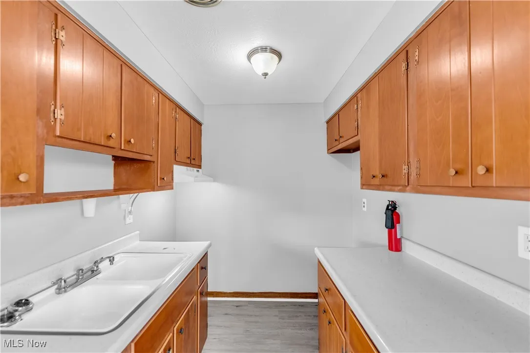 Laundry area featuring a sink and light wood-style floors