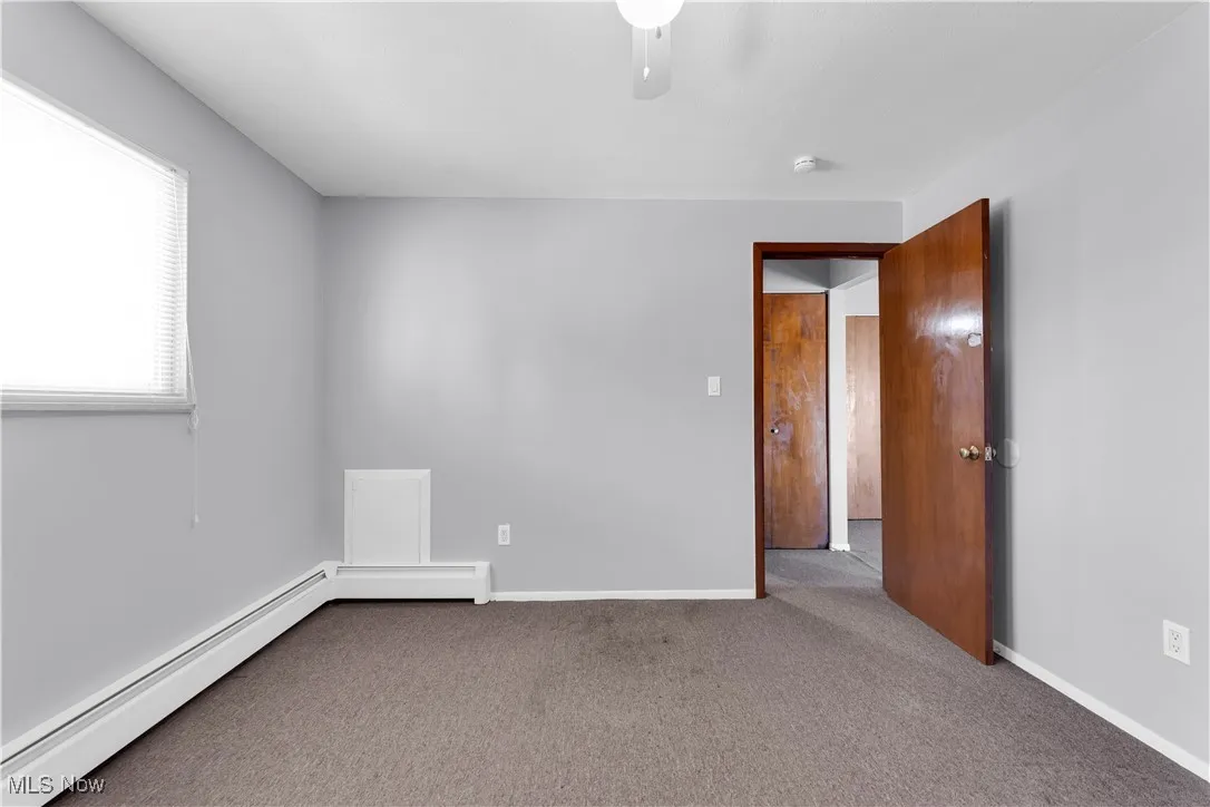 Unfurnished room featuring a baseboard heating unit and carpet flooring