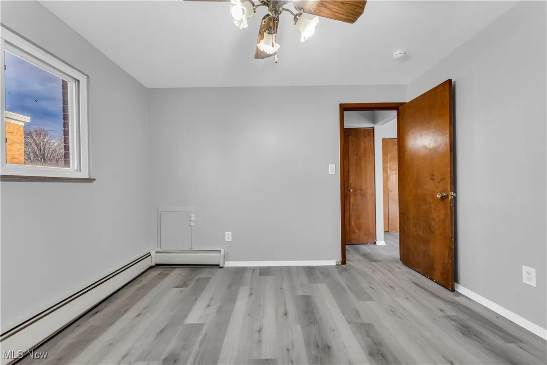 Spare room with baseboard heating, light wood-type flooring, and a ceiling fan