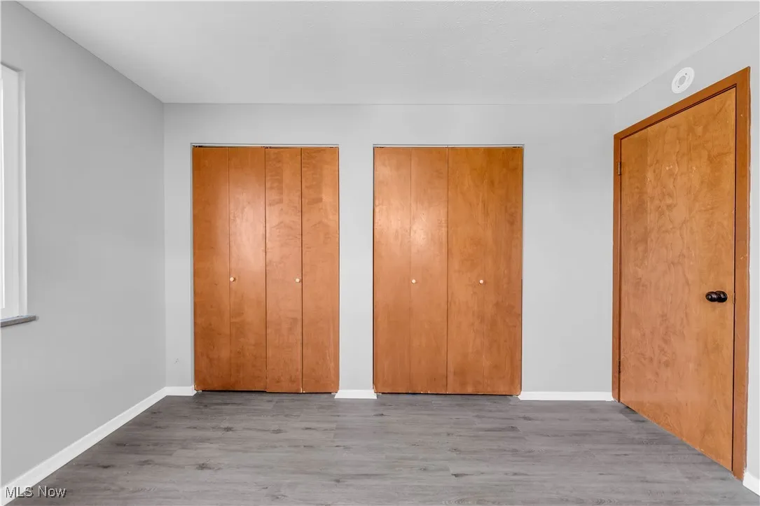Unfurnished bedroom featuring two closets and wood finished floors