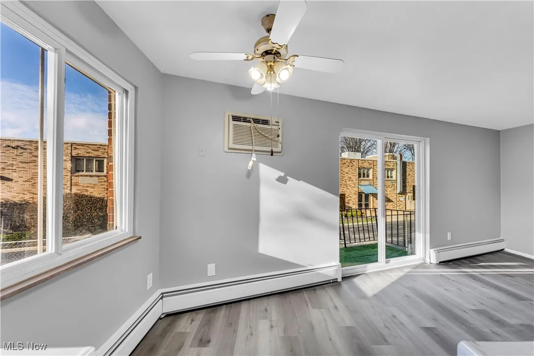 Unfurnished room with light wood-style flooring, a baseboard heating unit, a ceiling fan, and a wall mounted AC