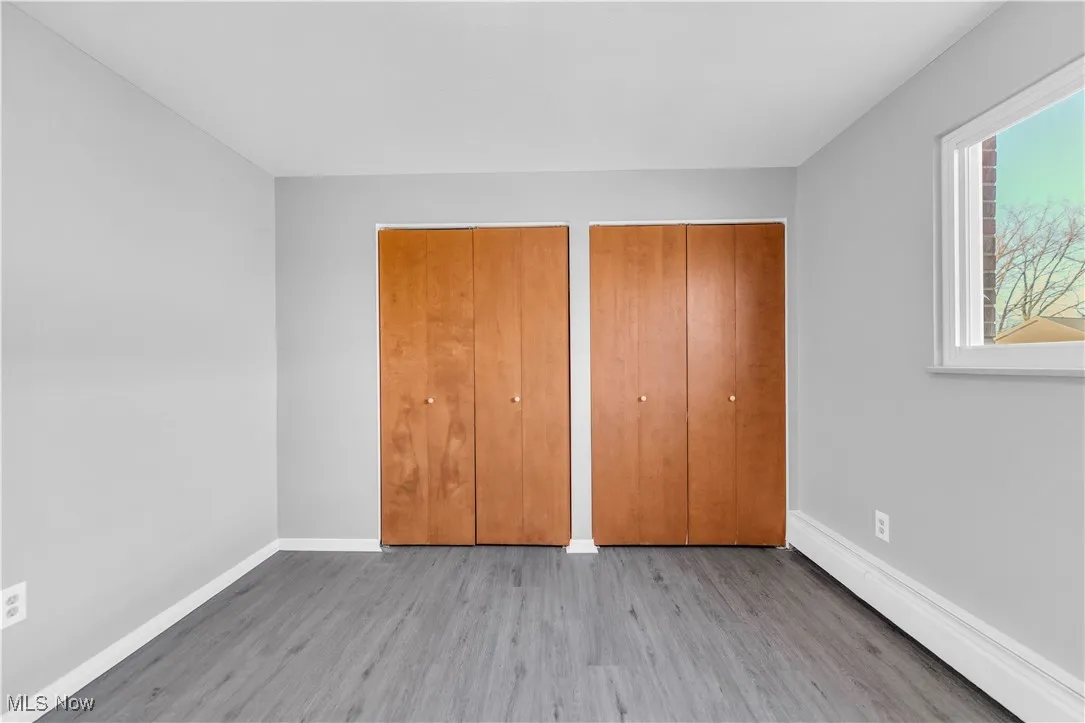 Unfurnished bedroom with wood finished floors and two closets