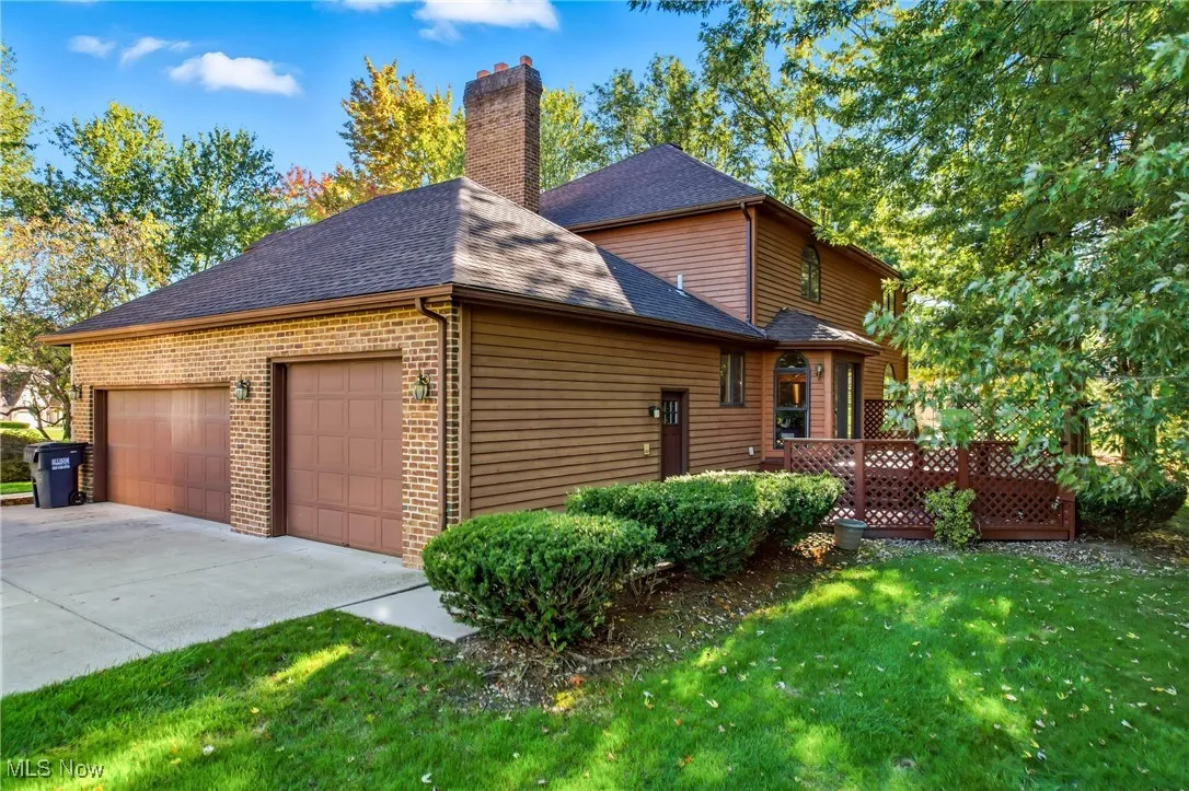 View of side of property featuring brick siding, a shingled roof, a lawn, concrete driveway, and a garage