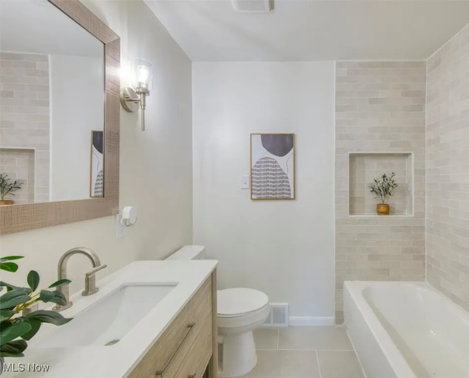Bathroom featuring light tile patterned floors, vanity, and tub / shower combination