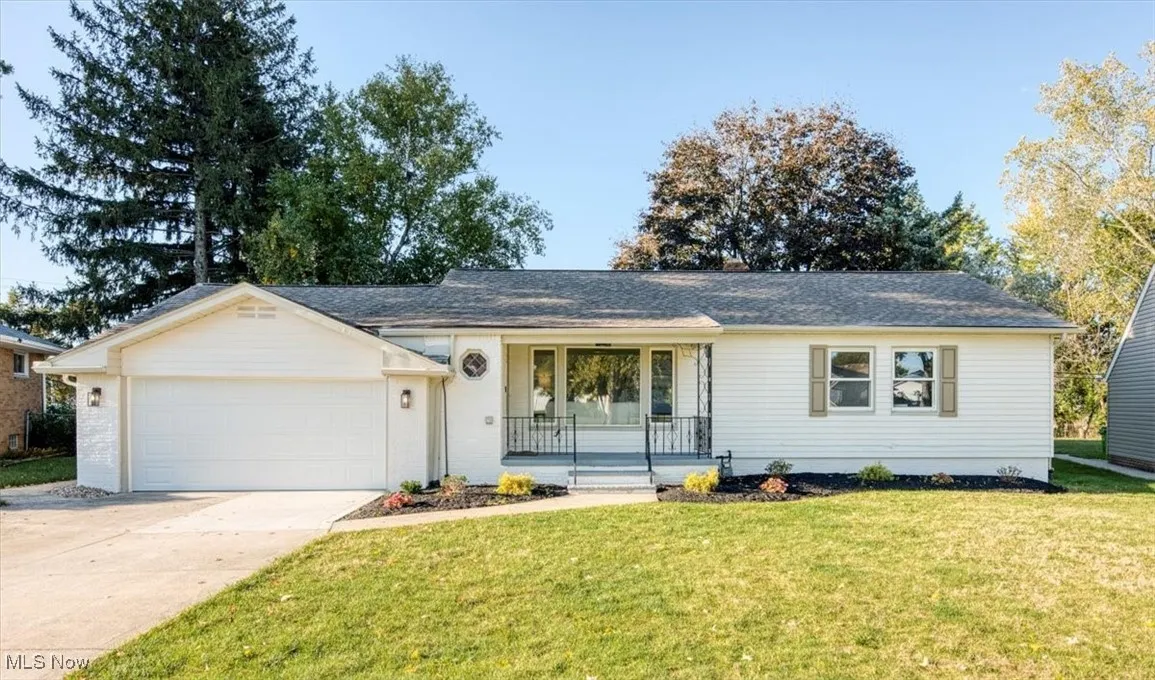 Ranch-style house with covered porch, a front yard, concrete driveway, an attached garage, and brick siding