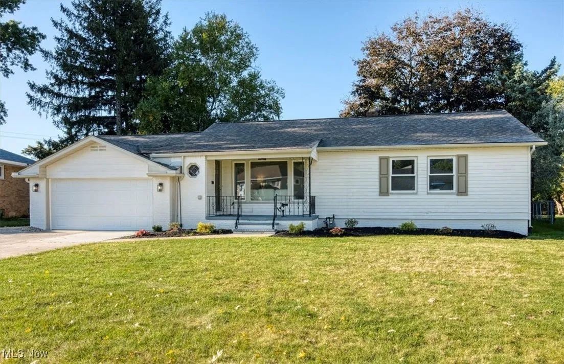 Ranch-style home featuring a porch, a front lawn, driveway, and a garage