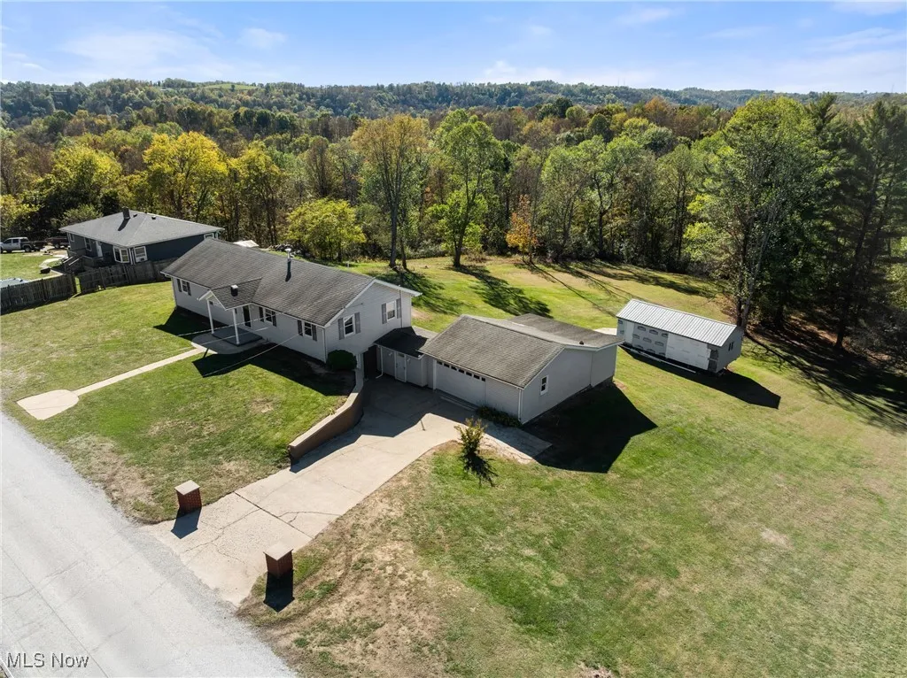 Aerial view of property and surrounding area with a heavily wooded area