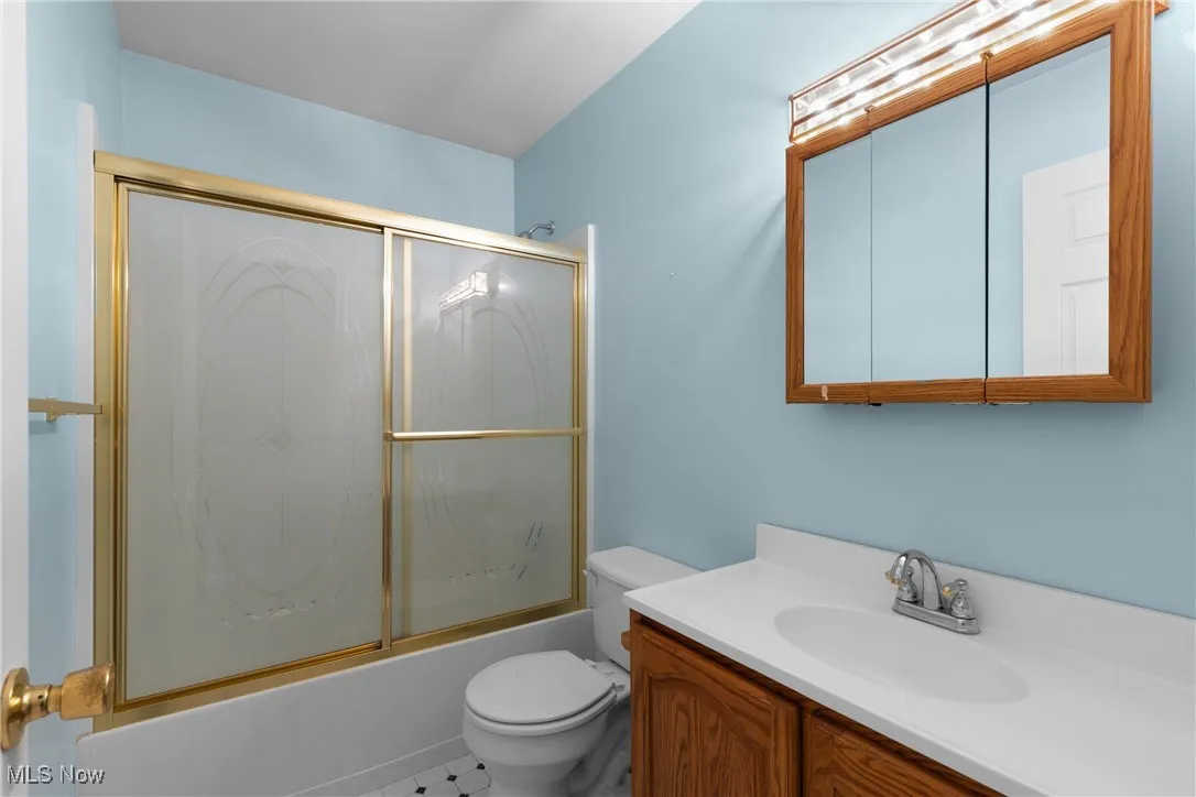 Bathroom with vanity, shower / bath combination with glass door, and tile patterned flooring