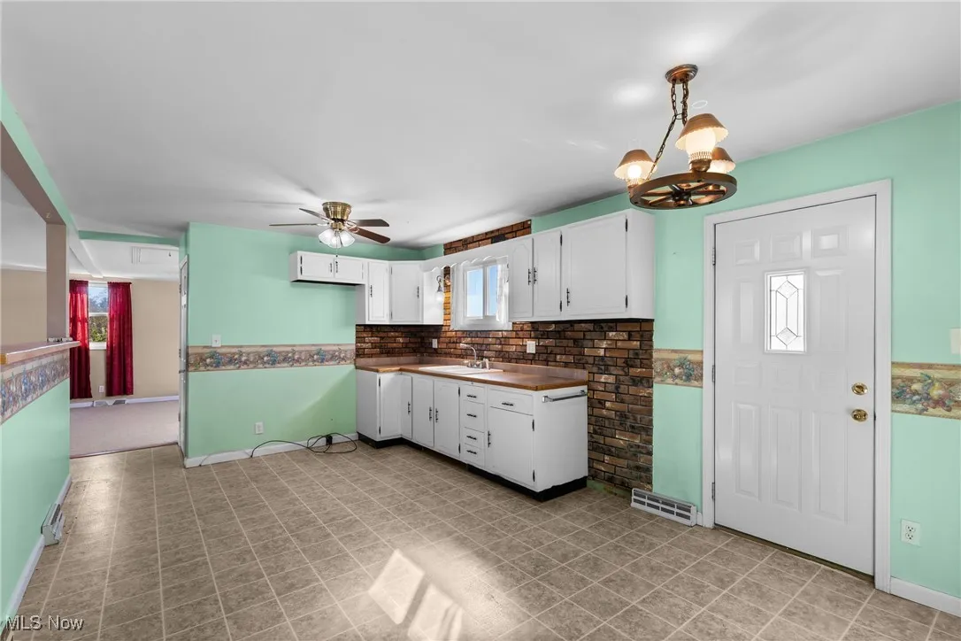 Kitchen featuring white cabinets, a chandelier, dark countertops, ceiling fan, and pendant lighting