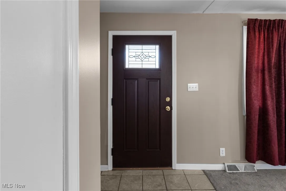 Tiled entryway featuring baseboards