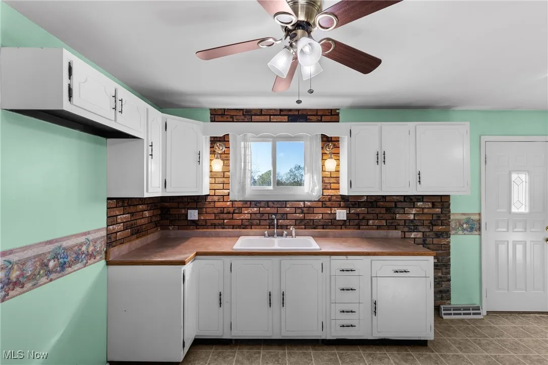 Kitchen featuring white cabinetry, dark countertops, and a ceiling fan