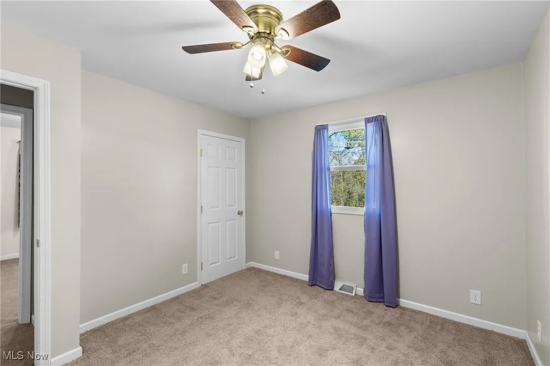 Unfurnished bedroom with light carpet and a ceiling fan