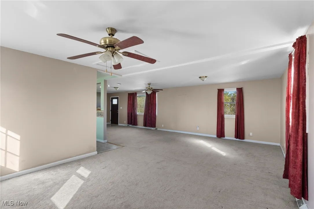 Unfurnished room with light colored carpet and ceiling fan