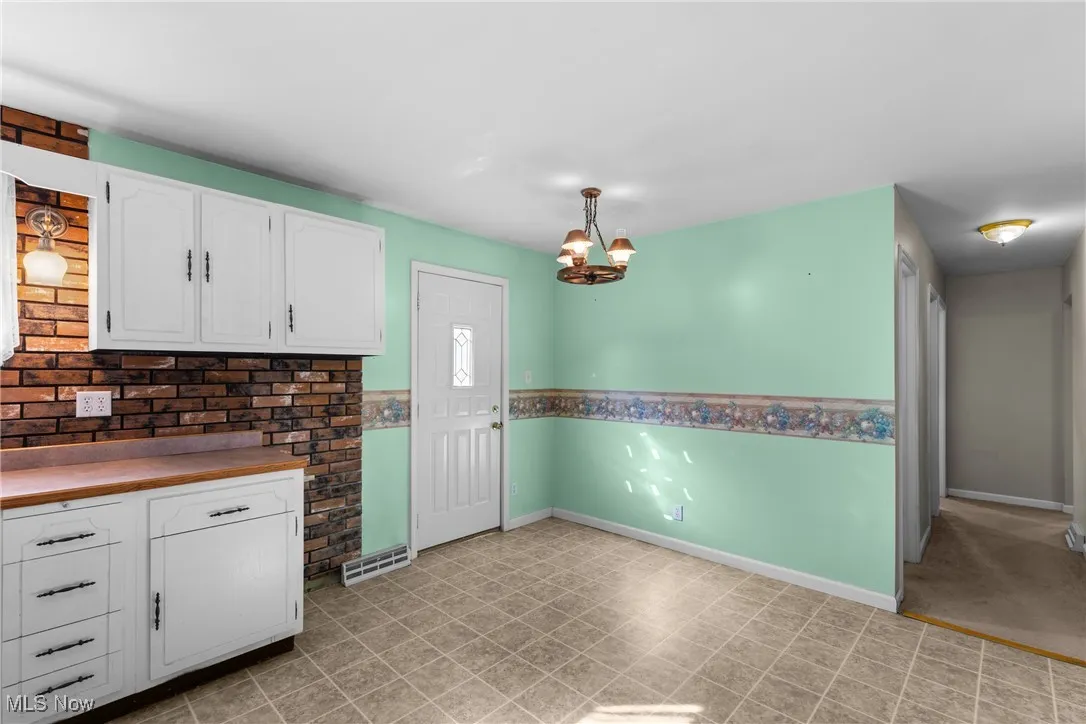 Kitchen with white cabinetry, a chandelier, hanging light fixtures, and butcher block countertops