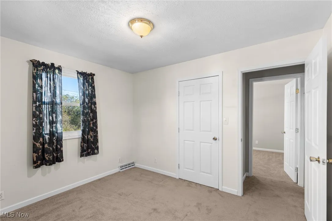 Unfurnished bedroom with light carpet and a textured ceiling