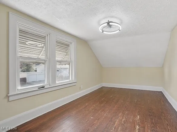 Bonus room featuring a textured ceiling, dark wood-style floors, and lofted ceiling