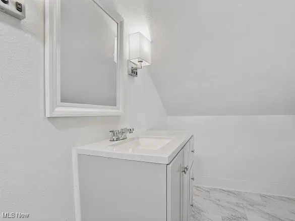 Bathroom with vanity and lofted ceiling