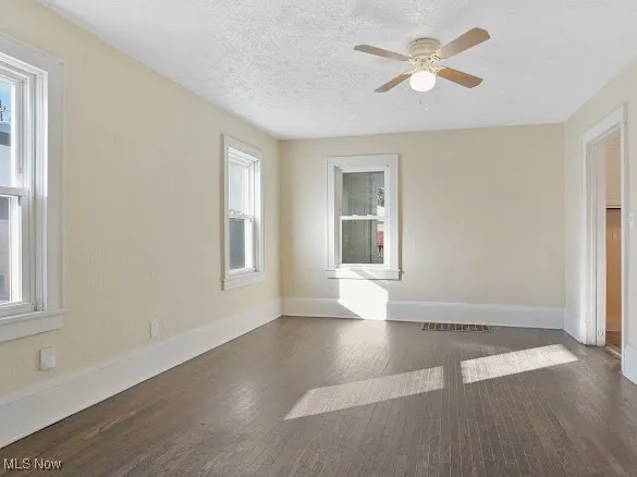Unfurnished room featuring dark wood finished floors, a textured ceiling, and ceiling fan