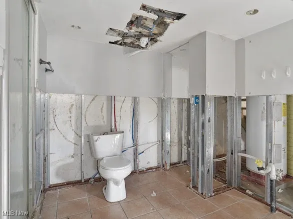 Full bath featuring water heater and tile patterned flooring