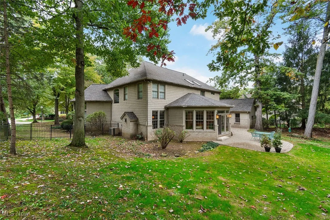 Back of house with a patio area, a sunroom, and a shingled roof