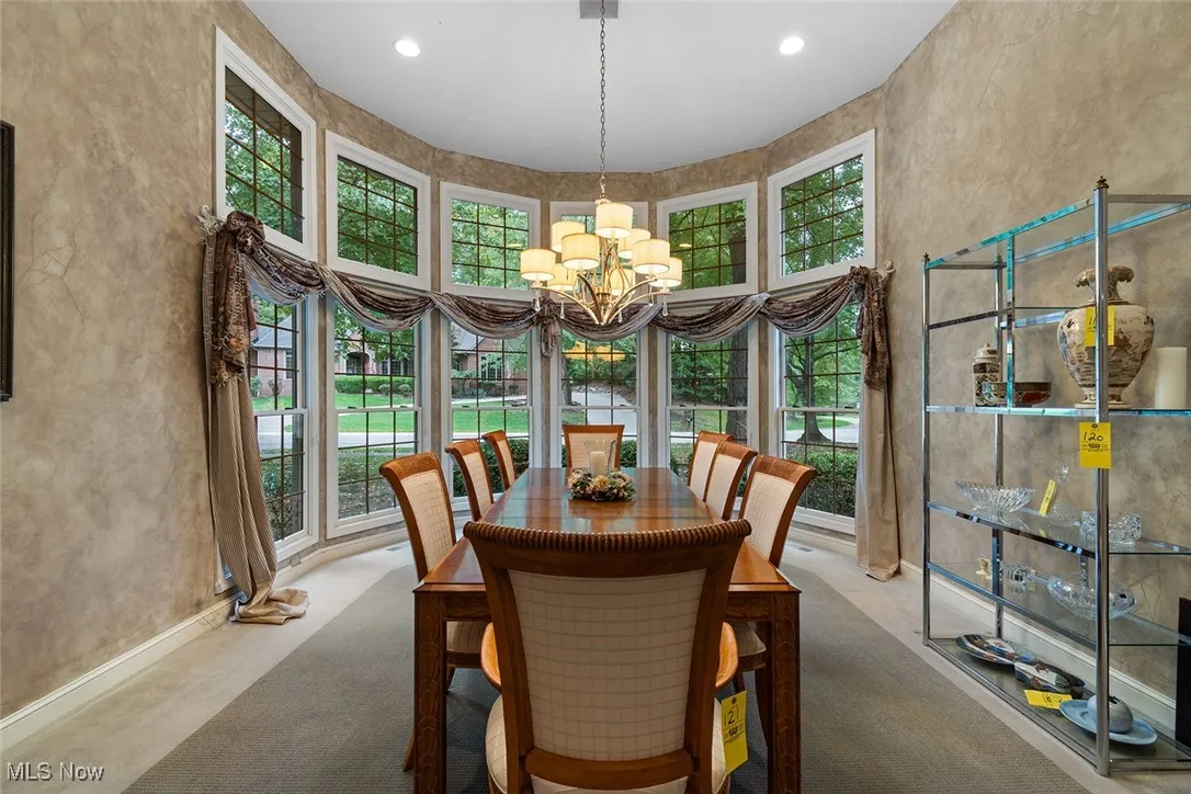 Dining room with healthy amount of natural light, a textured wall, a high ceiling, a chandelier, and recessed lighting