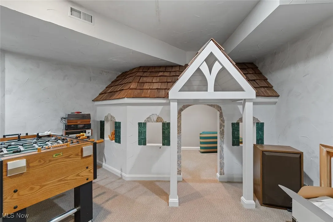 Recreation room featuring carpet floors and a textured wall