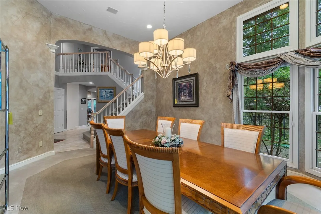 Dining room with a towering ceiling, a chandelier, stairway, and recessed lighting
