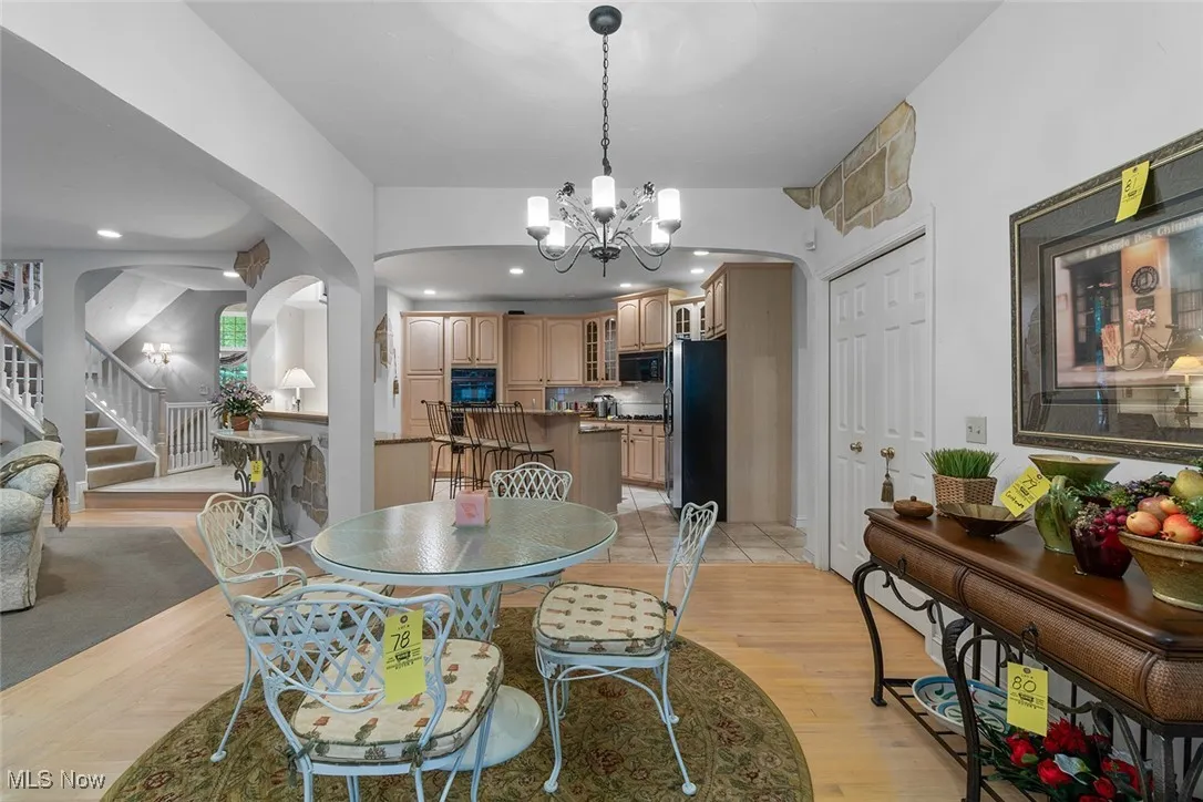 Dining area featuring arched walkways, stairs, a chandelier, light wood finished floors, and recessed lighting