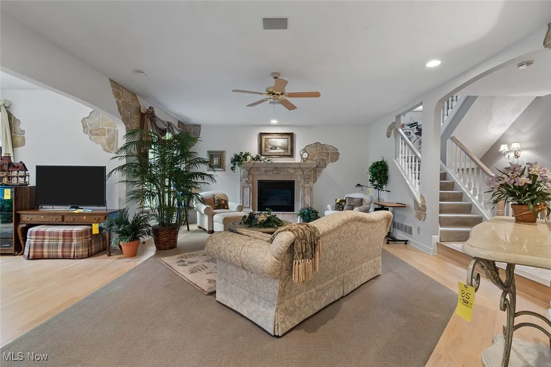 Living area with light wood-type flooring, a fireplace, stairway, ceiling fan, and recessed lighting