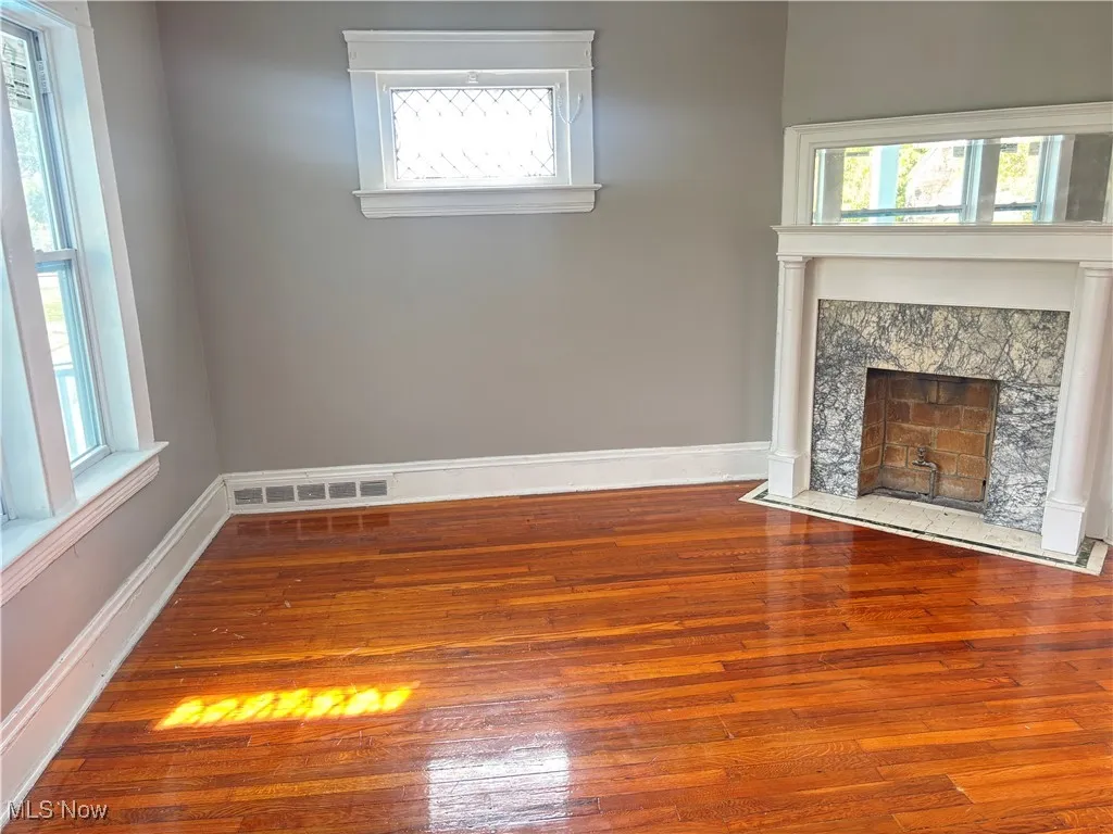 Unfurnished living room featuring hardwood / wood-style flooring and a high end fireplace