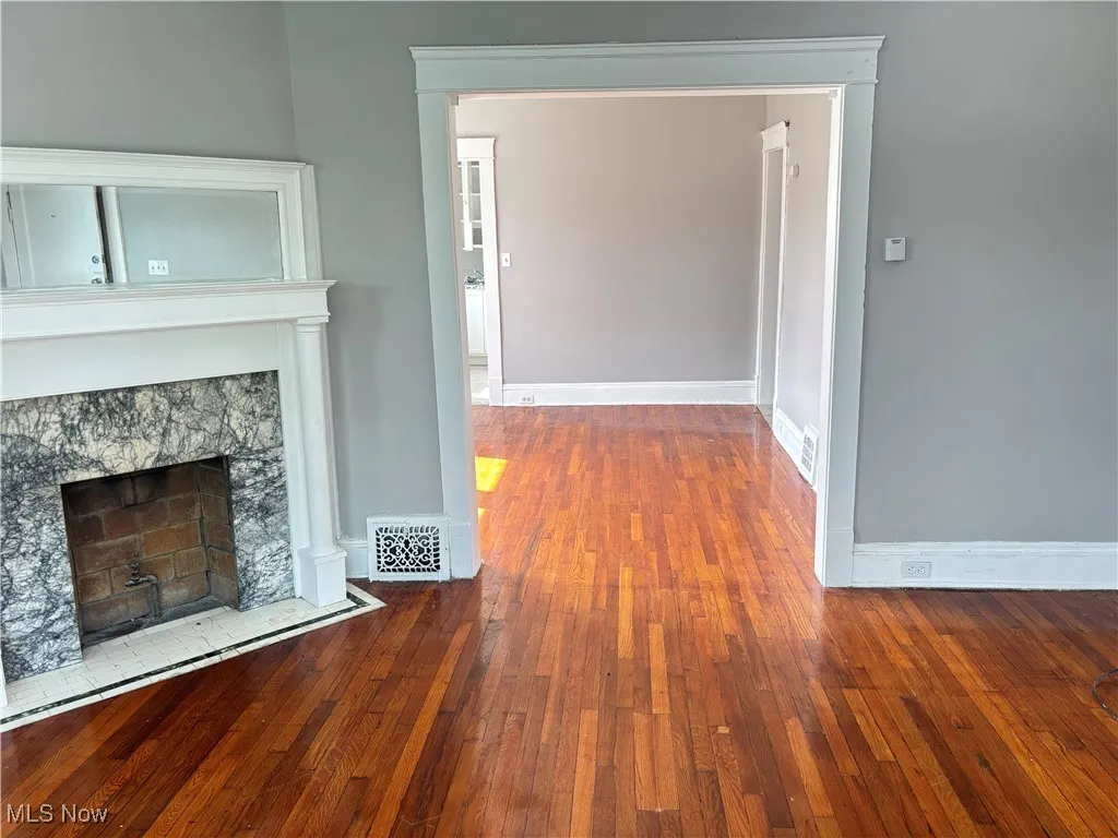 Unfurnished living room featuring dark wood-style floors and a fireplace
