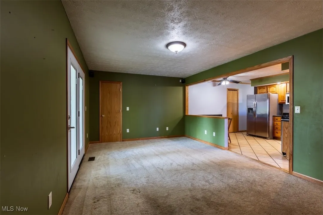 Unfurnished room featuring a textured ceiling and light carpet