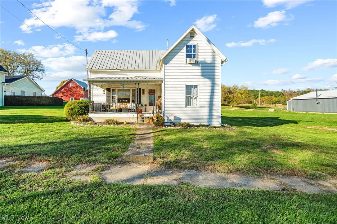 Back of property featuring a yard, a porch, and a metal roof