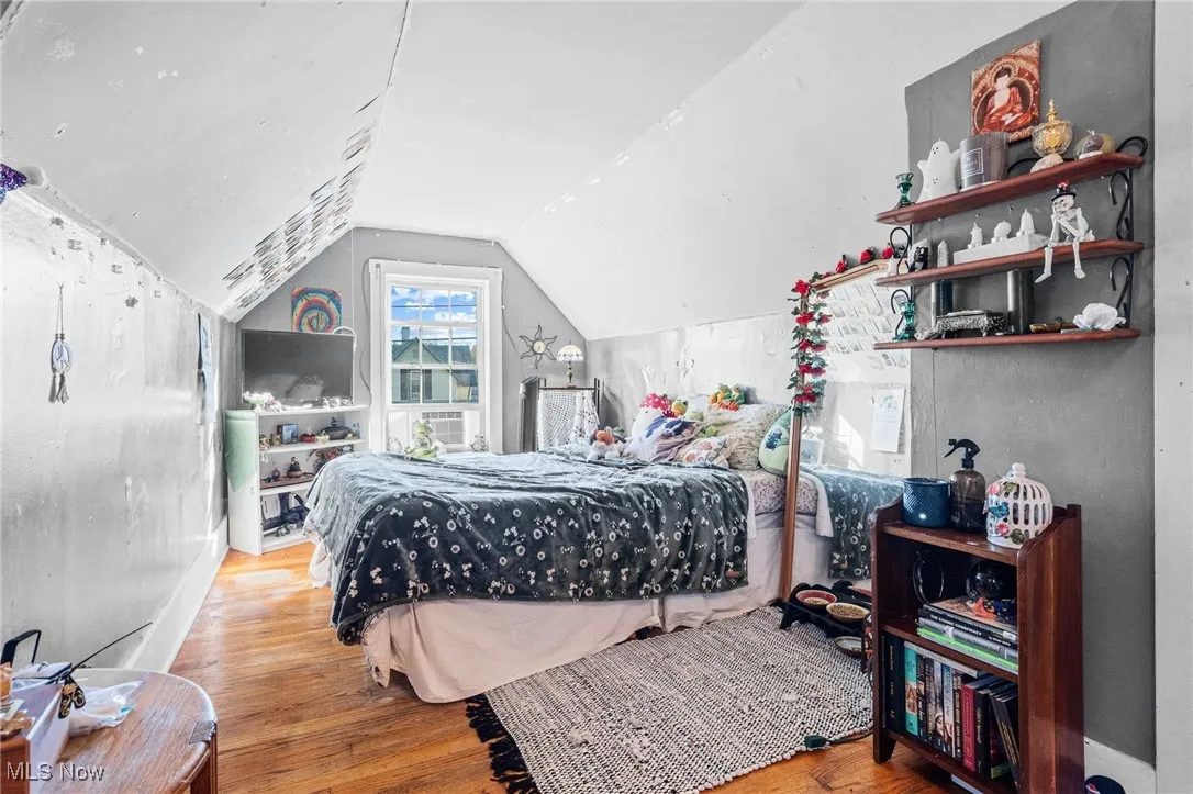 Bedroom featuring wood finished floors and vaulted ceiling