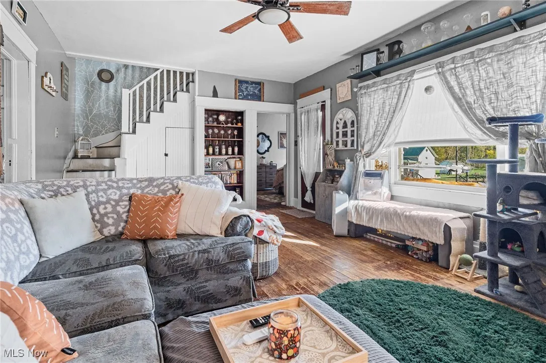 Living room with hardwood / wood-style floors, stairs, and ceiling fan