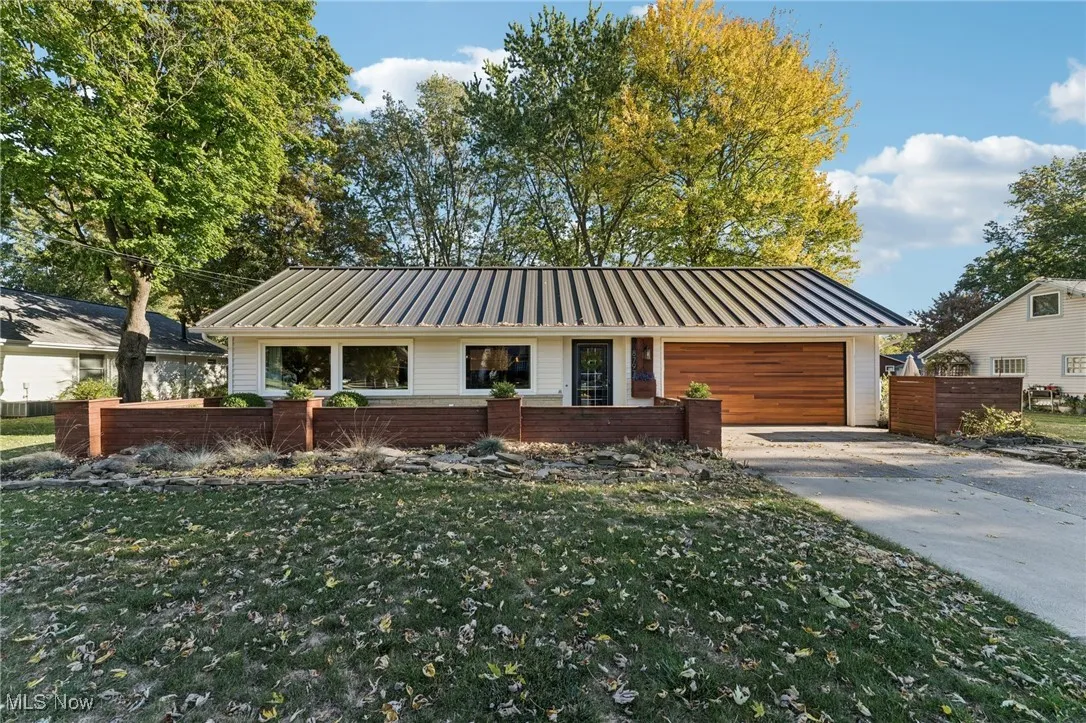 View of front of property with a standing seam roof, a metal roof, driveway, and a garage