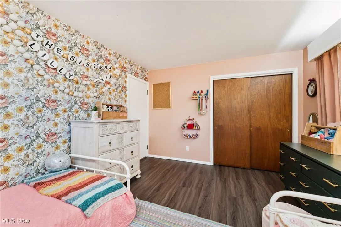 Bedroom featuring dark wood-type flooring, a closet, and wallpapered walls