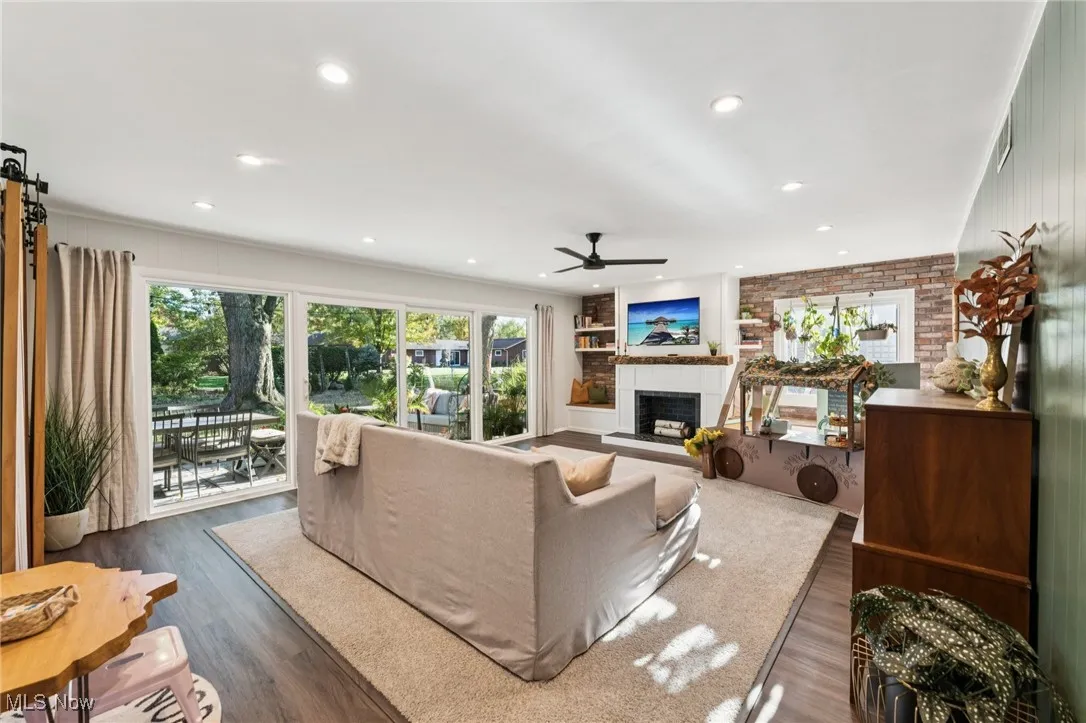 Living area with a fireplace with raised hearth, dark wood finished floors, ceiling fan, and recessed lighting