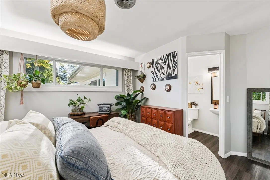 Bedroom with dark wood-style floors and connected bathroom