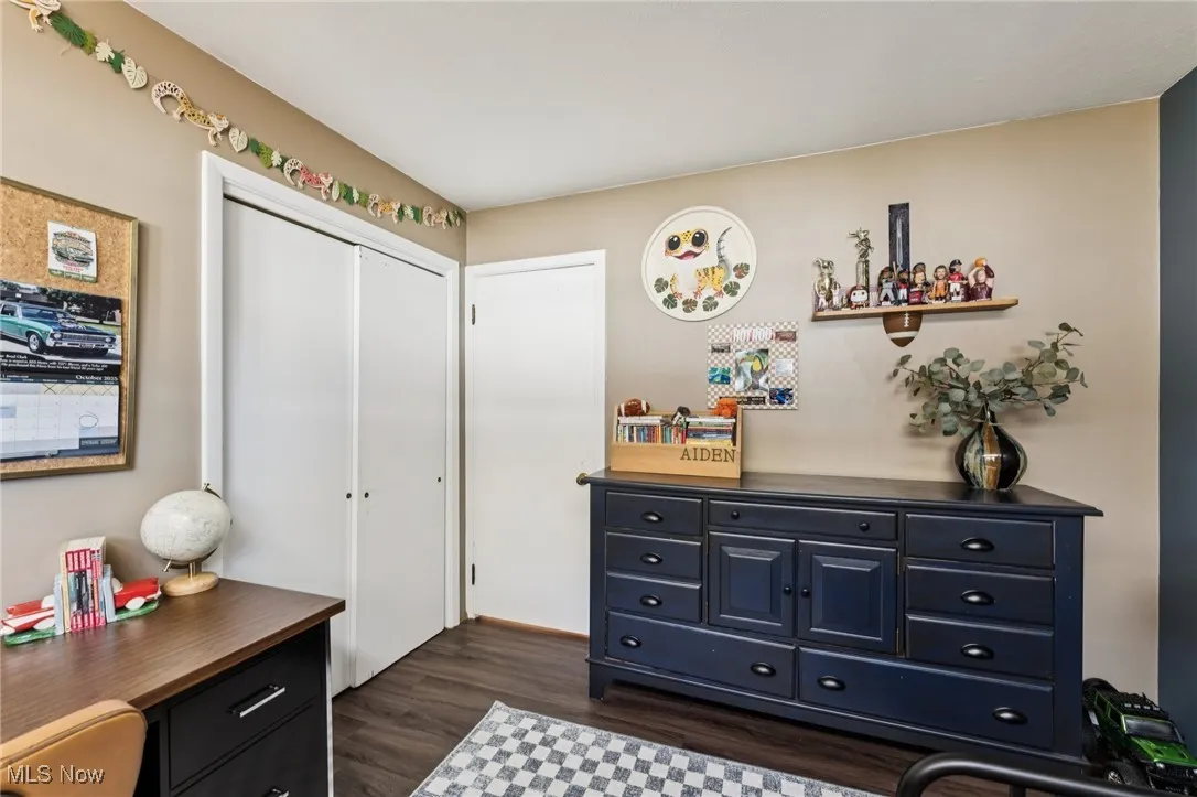 Bedroom with dark wood-style flooring and a closet